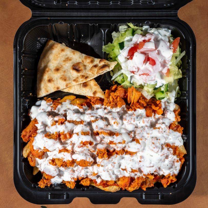 Zaytoon's Afghan chicken and fries, topped with white sauce, served with naan and salad.