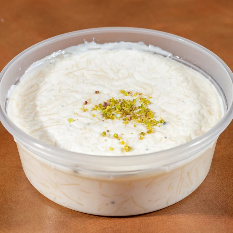 Zaytoon's Afghan dessert, Firni, a creamy pudding with vermicelli and pistachios in a clear container.